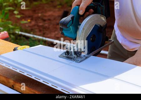 En cours de construction, l'artisan coupe des panneaux de parement en vinyle à la taille désirée avant de les installer Banque D'Images