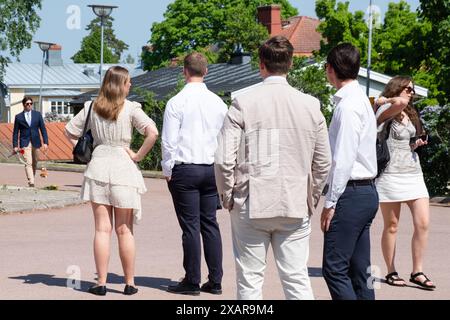 Les familles attendent devant le bâtiment principal de l’école pour la Journée de remise des diplômes Åland 2024 au Lyceum Åland (gymnase Ålands) à Mariehamn, archipel de Åland, mer Baltique, Finlande – c’est le jour où les élèves quittent l’école pour la dernière fois. Dans le cadre de cette tradition nordique, des pancartes sont tenues avec des photos de bébé des diplômés et les étudiants eux-mêmes portent leurs chapeaux de graduation de style marin (studentmössa) et s'habillent en costumes (garçons) et robes blanches (filles). Photo : Rob Watkins. Banque D'Images