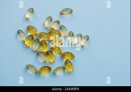 Nutrition et remplissage de vitamines dans la capsule de gélatine molle colorée. Capsules jaunes transparentes d'huile de poisson. Banque D'Images
