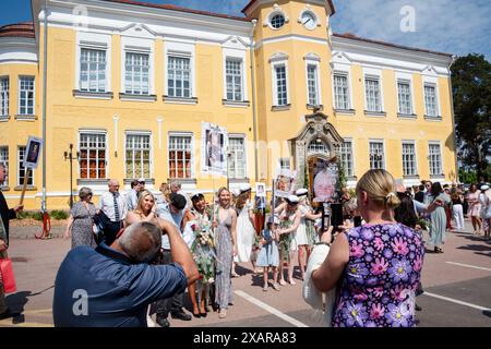 LES FILLES POSENT POUR UNE PHOTO DE GROUPE, REMISE DES DIPLÔMES DE Åland, MARIEHAMN : un grand groupe de jeunes filles diplômées posent pour une photo de célébration avec des fleurs et leurs pancartes de bébé à l'extérieur du bâtiment principal de l'école au jour de la remise des diplômes de Åland 2024 au Lyceum de Åland (gymnase de Ålands) à Mariehamn, archipel de Åland, mer Baltique, Finlande – C’est le jour où les élèves quittent l’école pour la dernière fois. Dans le cadre de cette tradition nordique, des pancartes sont tenues avec des photos de bébé des diplômés et les étudiants eux-mêmes portent leurs chapeaux de graduation de style marin (studentmössa) et s'habillent en costumes et robes blanches. Banque D'Images