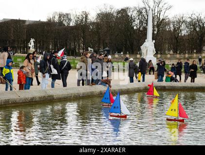 Parents regardant pendant que les enfants naviguent sur des bateaux jouets dans le jardin de Luxembourg à Paris, France Banque D'Images