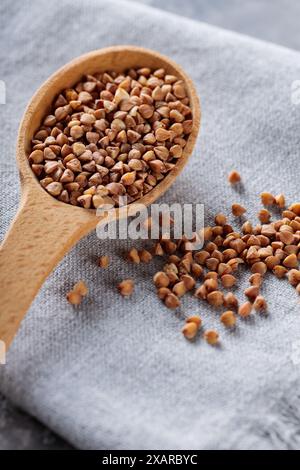 Grains de sarrasin en cuillère en bois sur serviette grise, gros plan Banque D'Images