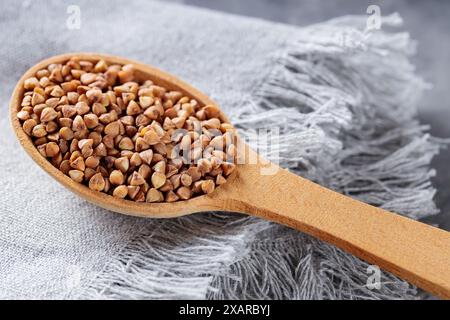 Grains de sarrasin en cuillère en bois sur serviette grise, gros plan Banque D'Images