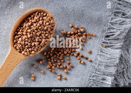 Grains de sarrasin en cuillère en bois sur serviette grise, gros plan Banque D'Images