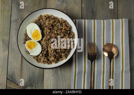 Porridge Grenne, moitiés d'œufs, fourchette, cuillère sur une serviette. Le concept de régime équilibré. Protéines, glucides. Banque D'Images