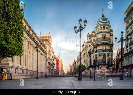 Une photo en exposition longue capture l'Avenida de la Constitucion vide à Séville, en Espagne, au coucher du soleil. L'image montre la rue bordée de bâtiments et St Banque D'Images