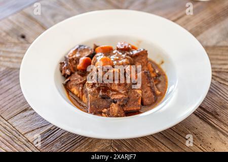 Gros plan du ragoût andalou traditionnel rabo de toro servi dans un bol blanc, mettant en valeur son aspect riche et copieux. Banque D'Images