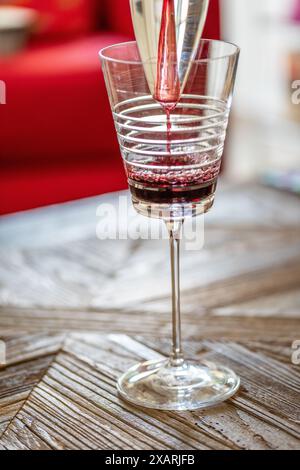 Gros plan de vin rouge versé dans un verre design à l'aide d'un aérateur sur une table en bois. Banque D'Images