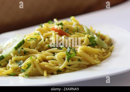 Gros plan de bami goreng garni de céleri et de carottes tranchées, mie goreng sur une plaque blanche avec mise au point sélective. Nouilles frites indonésiennes avec Banque D'Images