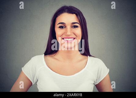 Portrait d'une femme souriante isolée sur un fond de mur gris Banque D'Images