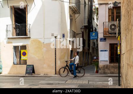 VALENCE, ESPAGNE - 2 mai 2024 : une femme sur un vélo loué profite des vues sur Carrer de la Corretgeria Banque D'Images