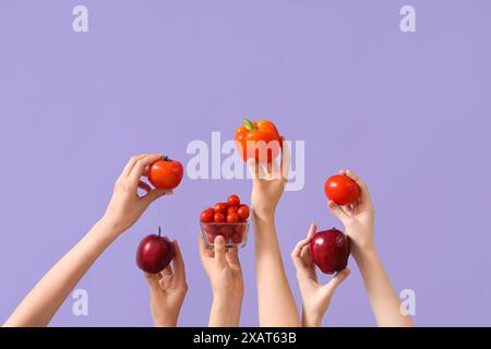 Mains avec tomates fraîches, pommes et poivrons sur fond lilas Banque D'Images