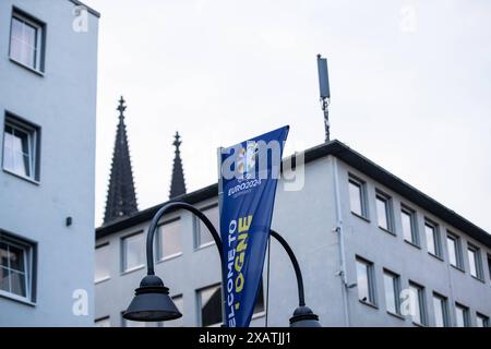 EURO 2024 in Köln, Stilisierte Schilder in der Stadt 08.06.2024 Eine Flagge mit dem logo von EURO 2024, Festival in Köln, Cologne, ville hôte. Auf dem Hintergrund sieht man Kölner Dom. EURO 2024 in Köln, Stilisierte Schilder in der Stadt 08.06.2024 Köln Innenstadt NRW Deutschland *** EURO 2024 in Cologne, signes stylisés dans la ville 08 06 2024 Un drapeau avec le logo de l'EURO 2024, Festival in Cologne, Cologne, ville hôte sur le fond, vous pouvez voir la cathédrale de Cologne EURO 2024 à Cologne, panneaux stylisés dans la ville 08 06 2024 Cologne centre ville NRW Allemagne Copyright : xBEAUTIFULxSPORTS/Buriakovx Banque D'Images