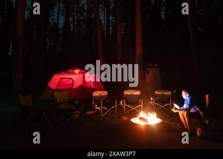 Une tente est éclairée de l'intérieur dans un terrain de camping forestier Banque D'Images