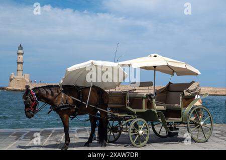 Vieille ville de Chania, Crète, Grèce. Calèche blanche tirée par des chevaux et phare dans le port vénitien, Banque D'Images