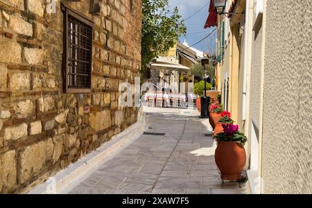 Athènes, Grèce. Taverne traditionnelle grecque en plein air table vide et chaise à Plaka. Plante en pot sur allée pavée, bâtiment en pierre, journée d'été. Banque D'Images