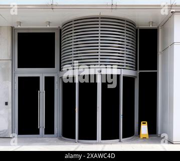 Une porte tournante ronde est installée à l'entrée d'un immeuble de bureaux en verre Banque D'Images