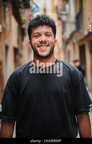 Portrait individuel vertical d'un homme arabe souriant et regardant la caméra à l'extérieur. Jeune homme arabe adulte regardant devant et riant avec une expression amicale. Homme joyeux avec attitude insouciante. Photo de haute qualité Banque D'Images