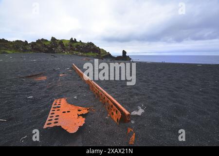 Des parties d'un navire font naufrage sur la plage noire Banque D'Images