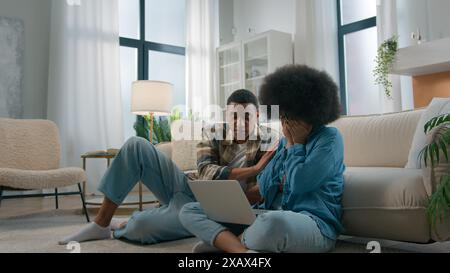 Couple afro-américain assis sur le sol à la maison salon femme fille épouse bouleversée triste souffrir problème avec l'erreur d'ordinateur portable erreur crash en ligne perdu Banque D'Images