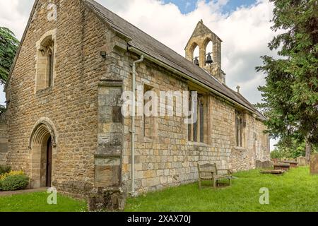 L'église de campagne de Saint Everilda à Poppleton près de York. Un banc est placé contre un mur et un clocher est au-dessus. Banque D'Images