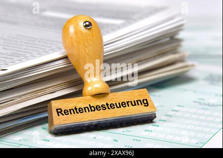 Rentenbesteuerung gedruckt auf Holzstempel Ein Holzstempel lehnt an einem Stapel Formulare mit der Aufschrift Rentenbesteuerung *** pension taxation p Banque D'Images