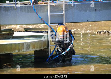 Plongeur grimpe dans le réservoir d'aération dans une station d'épuration Banque D'Images