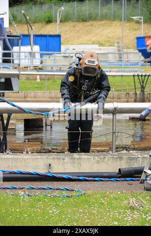 Plongeur grimpe dans le réservoir d'aération dans une station d'épuration Banque D'Images