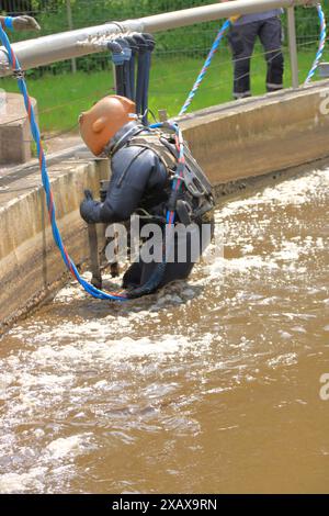 Plongeur grimpe dans le réservoir d'aération dans une station d'épuration Banque D'Images