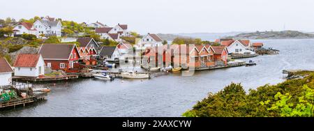 Charmants cottages rouges et blancs au bord de l'eau, avec des bateaux amarrés le long de la jetée. Destinations froides tendance de voyage. Kristiansand, Norvège Banque D'Images