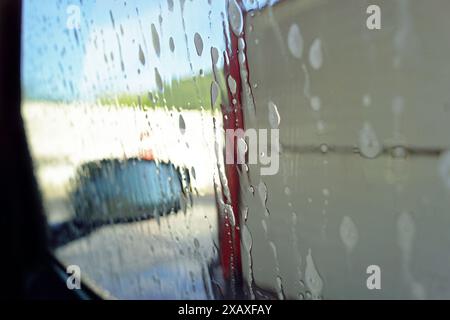 Lavage d'une voiture dans un lave-auto à ciel ouvert : photographie en gros plan de mousse sur la vitre latérale d'une voiture. Banque D'Images