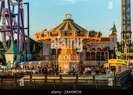 Gröna Lund sur l'île-musée de Djurgården a été fondée en 1883 par l'Allemand Jacob Schultheiss et est le plus ancien parc d'attractions de Suède. Le parc d'attractions est divisé en une ancienne et une nouvelle partie. Voici le carrousel de chaîne nostalgique dans le soleil du soir. Il est situé directement sur l'eau. Carrousel à chaînes à Gröna Lund Tivoli. Parc d'attractions saisonnier avec montagnes russes et manèges à sensations fortes, jeux compétitifs et concerts. Djurgårdsstaden, Stockholm, Suède Banque D'Images