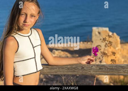 Ce pittoresque portrait de vacances à la montagne présente une belle jeune fille aux longs cheveux blonds et aux yeux verts. Banque D'Images