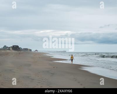 Femelle célibataire pieds nus marchant le long du rivage de l'océan Atlantique vers Rodanthe Pier sur Cape Hatteras en Caroline du Nord, États-Unis Banque D'Images