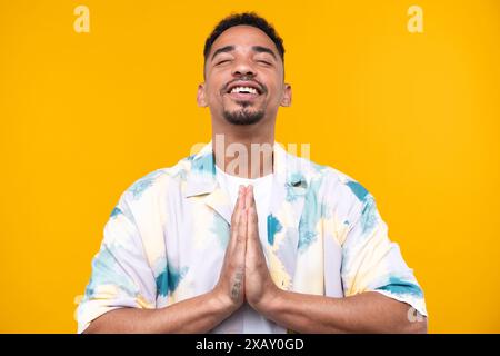 Émotionnel jeune homme noir dans l'ambiance décontractée levant les poings en arrière-plan de studio, célébrant le succès, heureux homme afro-américain millénaire partageant de bonnes émotions. Banque D'Images