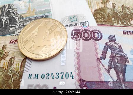 Gros plan sur une pièce de Litecoin dorée au-dessus d'une pile de billets de banque en rouble russe. Banque D'Images