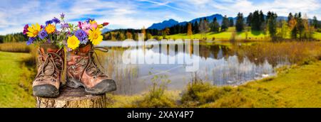 Wanderstiefel mit Blumen Ein Paar Wanderstiefel gefüllt mit einem Strauß Blumen, steht auf einer Blumenwiese vor einem malerischen See im Allgäu - fot Banque D'Images