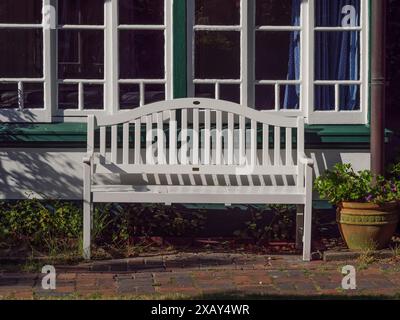 Banc blanc devant une fenêtre dans une maison avec des cadres de fenêtres verts et un pot de fleurs, Spiekeroog, Frise orientale, ALLEMAGNE Banque D'Images