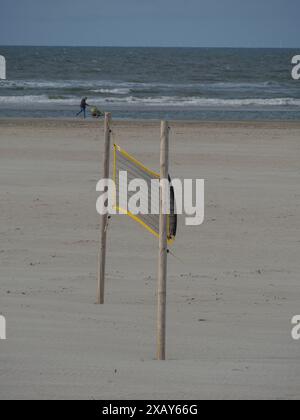 Un filet de volley-ball sur une plage de sable avec une personne et la mer en arrière-plan, juist, frise orientale, allemagne Banque D'Images