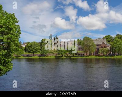 Vue sur une rivière à un rivage avec des arbres et des bâtiments historiques sous un ciel bleu avec quelques nuages, inverness, Écosse, Royaume-Uni Banque D'Images