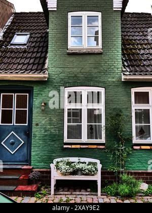 Une maison verte avec des fenêtres blanches, une porte bleue et un banc devant elle, Eckernfoerde, Schleswig-Holstein, Allemagne Banque D'Images