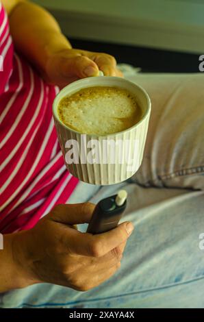 Femelle avec une cigarette électronique et une tasse de café dans la terrasse. Photo de haute qualité Banque D'Images