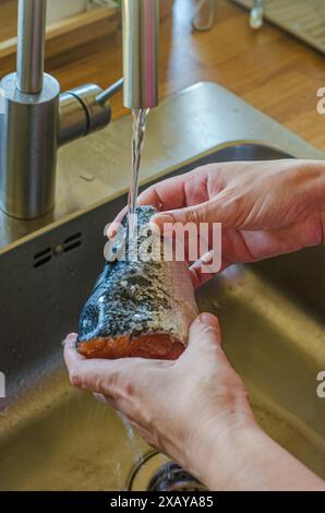 Les femmes nettoient et lavent une partie du saumon avec les mains. Photo de haute qualité Banque D'Images