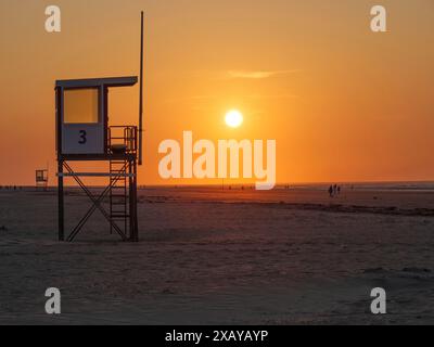 Une tour de sauvetage contre la silhouette d'un coucher de soleil orange vif sur la plage, juist, frise orientale, allemagne Banque D'Images