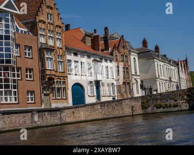 Une rangée de maisons historiques en briques le long d'un canal par une journée ensoleillée, Bruges, Belgique Banque D'Images