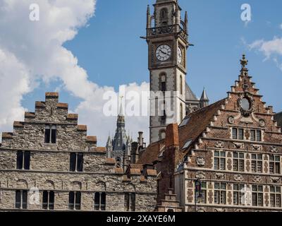 Bâtiments historiques avec un clocher en arrière-plan sous un ciel bleu avec quelques nuages, Gand, Belgique Banque D'Images