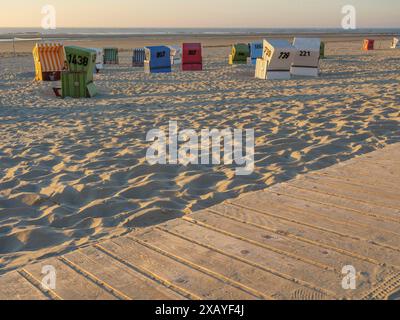 Une promenade en bois mène devant des chaises de plage colorées sur la plage de sable tranquille, langeoog, en allemagne Banque D'Images