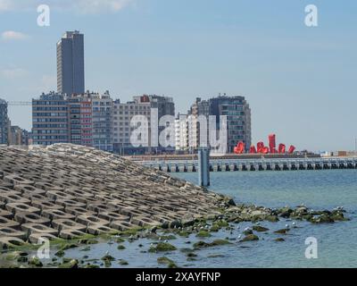 Littoral avec brise-lames, mer et ville en arrière-plan, ciel nuageux clair, ostende, Belgique Banque D'Images