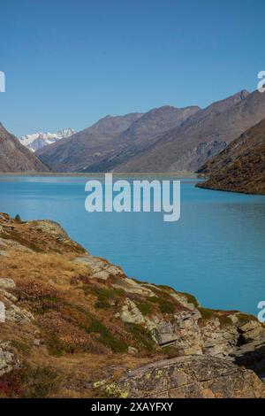 Un lac pittoresque dans une vallée entourée de montagnes, avec un ciel bleu clair et des rives rocheuses, saas Fee, suisse Banque D'Images