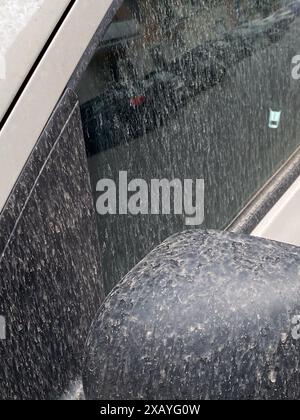 Cremona, Italie - 9 juin 2024 voiture argentée garée dans une rue de la ville est couverte d'une épaisse couche de poussière après une tempête de sable, concept de changement climatique Banque D'Images